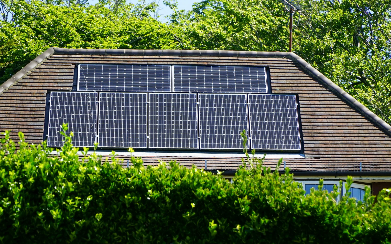 Panneaux photovoltaïques intégrés à la toiture d'une maison entourée de verdure